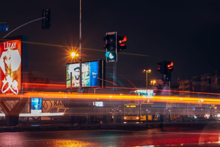 Illuminated outdoor billboards beside a busy road at night